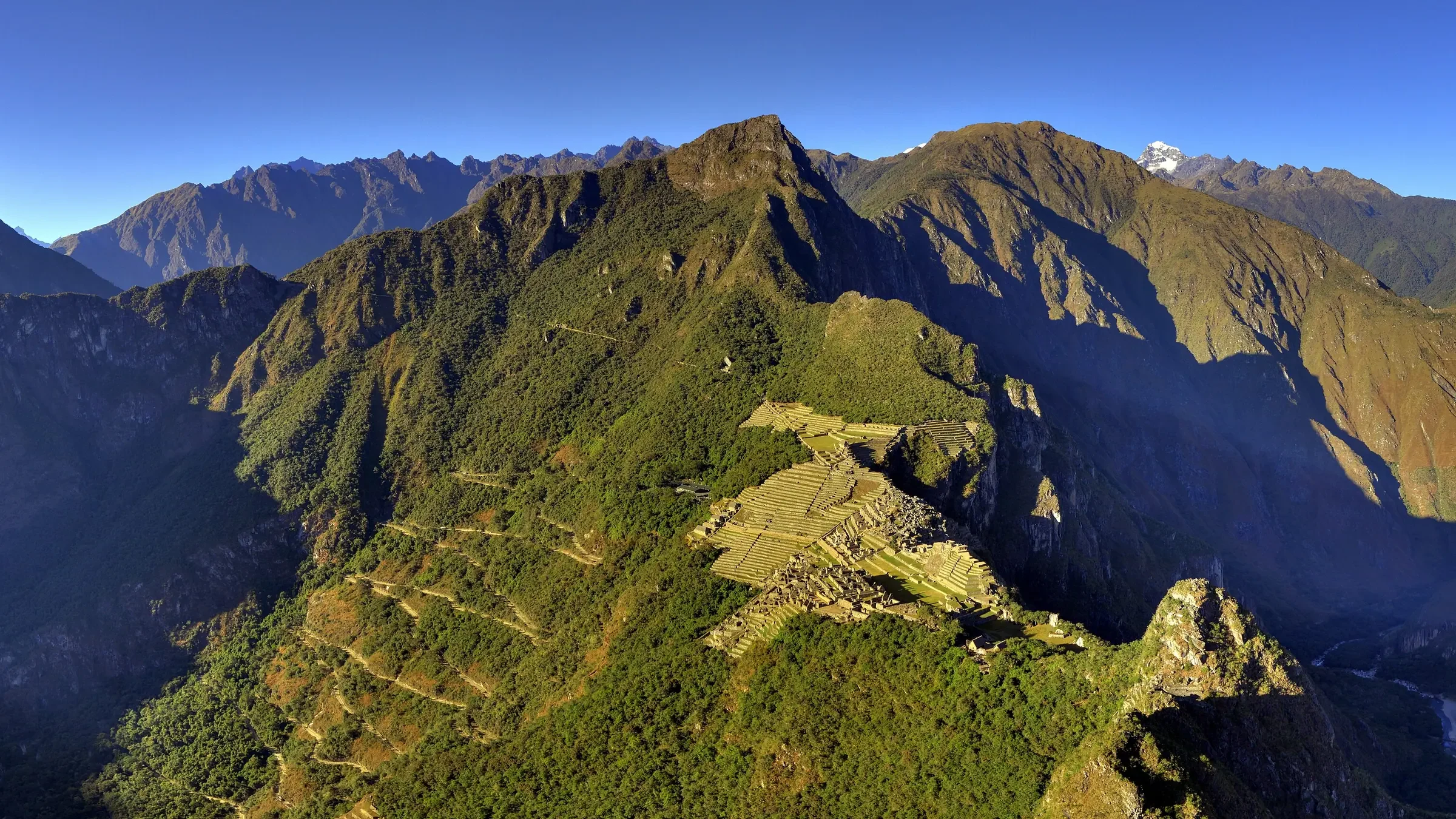 Panoramic view of Machu Picchu from Huayna Picchu, with the citadel on a mountaintop between Andean valleys and peaks